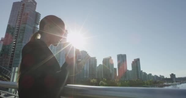 Femme d'affaires confiante utilisant le téléphone portable tout en prenant un café le jour ensoleillé — Video