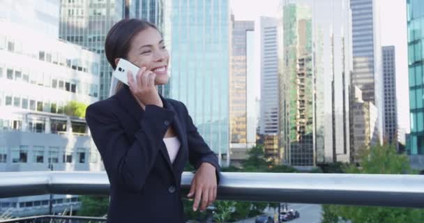 Empresária sorridente conversando no telefone celular por trilhos contra edifícios da cidade — Vídeo de Stock