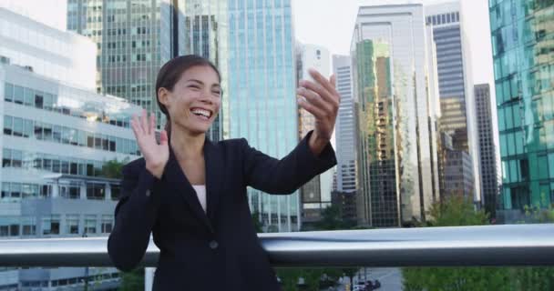 Souriant jeune femme d'affaires saluant sur vidéo chat application de téléphone portable en ville — Video