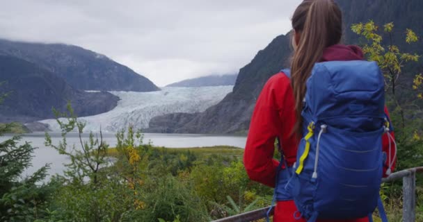 Пешая женщина в рюкзаке на Аляске смотрит на ледниковый пейзаж — стоковое видео