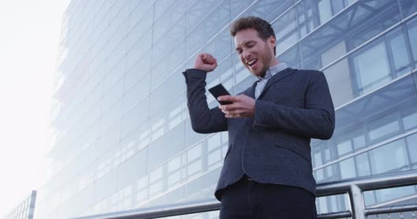 Geschäftserfolg und Erfolg - glücklicher Geschäftsmann jubelt mit Handy — Stockvideo