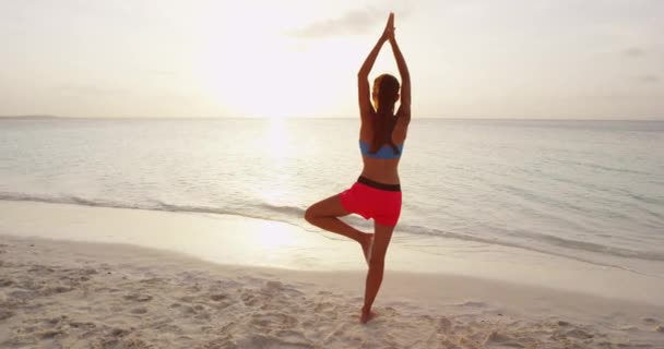 Yoga femme pose à la plage faisant yoga arbre pose au lever du soleil — Video