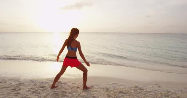 Postura de la mujer del yoga en la playa haciendo el ángulo lateral extendido Postura del yoga — Vídeo de stock