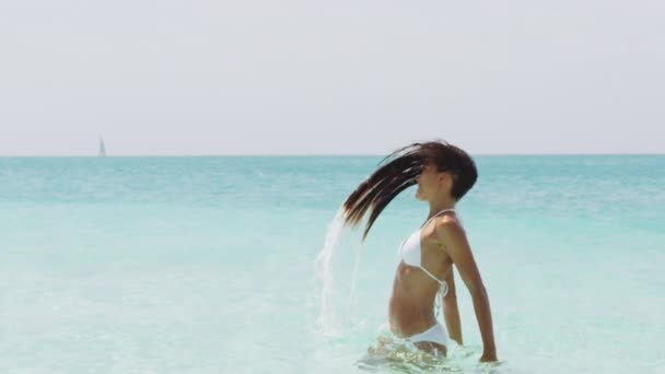 Flip de salpicadura de agua para el cabello - Sexy hermosa chica con el pelo largo en bikini en la playa — Vídeo de stock