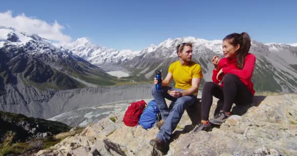 マウントクックによってニュージーランドの高山ハイキングで食事休憩を取るハイキングカップル — ストック動画