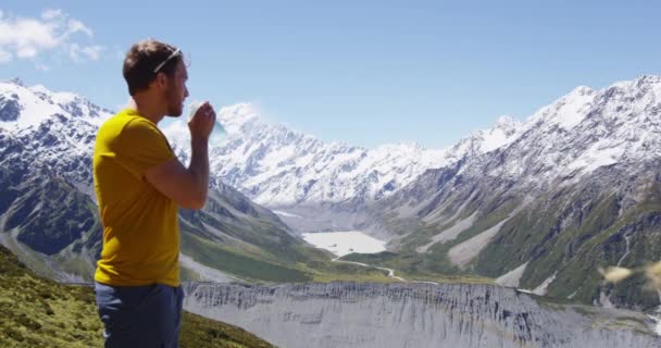 Man drinkwater wandelen in de voorkant van Mount Cook in Nieuw-Zeeland — Stockvideo