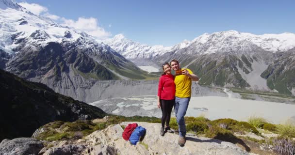 Backpackers pareja de senderismo tomando selfie teléfono en Mount Cook vista en Nueva Zelanda — Vídeos de Stock