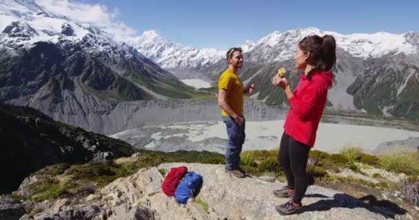 マウントクックによってニュージーランドの高山ハイキングで食事休憩を取るハイキングカップル — ストック動画