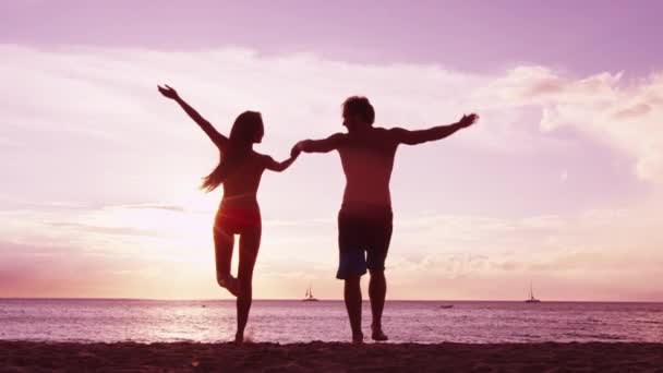 Feliz casal torcendo na praia desfrutando do pôr do sol em férias de viagem de verão — Vídeo de Stock