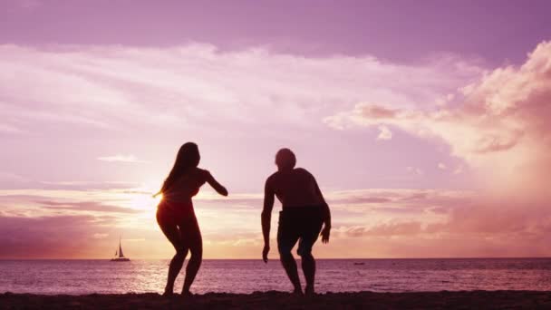 夏の旅行休暇の休日に夕日を楽しむビーチでジャンプする幸せなカップル — ストック動画