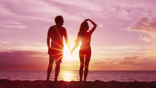Romantisch paar hand in hand op het strand bij zonsondergang met verbazingwekkend licht en kleuren — Stockvideo