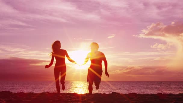 Praia casal de mãos dadas na praia desfrutar do pôr do sol correndo se divertindo em viagem — Vídeo de Stock