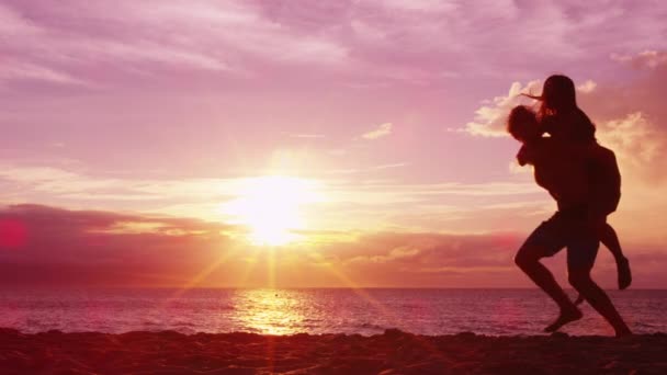 Casal piggybacking na praia se divertindo apreciando o pôr do sol em viagem de lua de mel — Vídeo de Stock