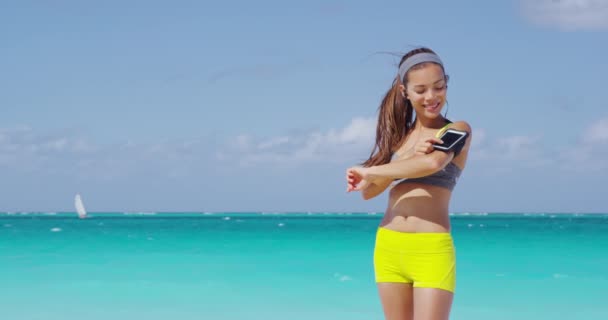 Fit femme en utilisant l'application de fitness smartphone sur le brassard — Video