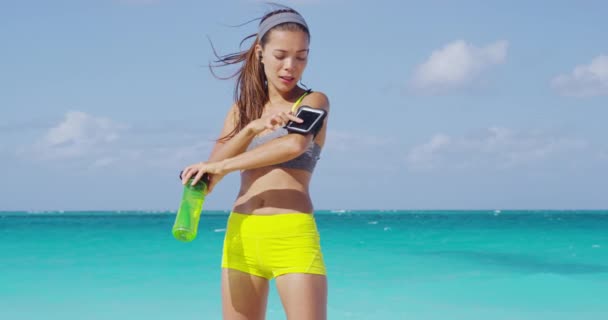 Žena běžec nosí sluchátka a chytrý telefon běží náramek — Stock video