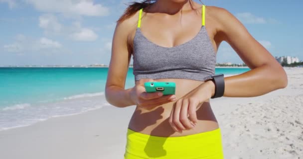 Mulher fitness vestindo smartwatch tocando e deslizando tela sincronização com telefone — Vídeo de Stock