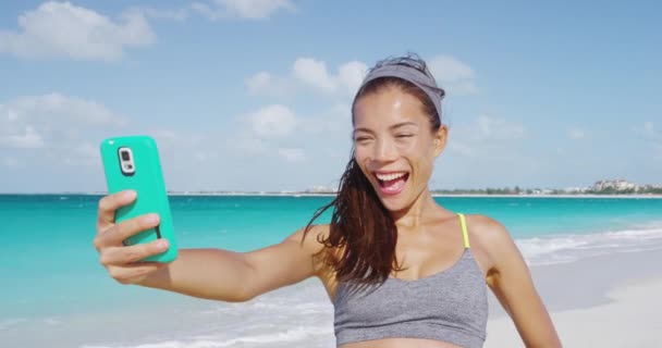 Kumsalda koştuktan sonra telefonla selfie çeken mutlu kız. — Stok video