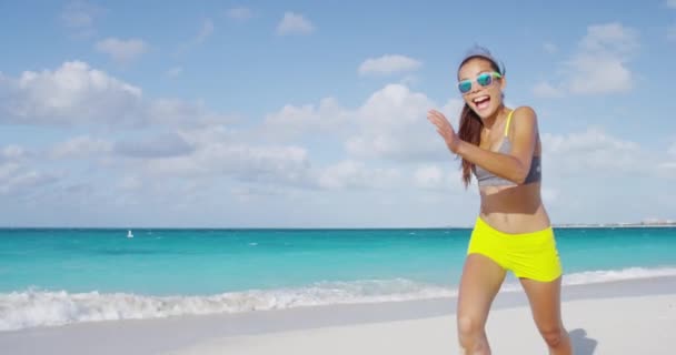 Παιχνιδιάρικη χαρούμενη αθλητική γυναίκα που χορεύει τρέχοντας διασκεδάζοντας στις διακοπές στην παραλία — Αρχείο Βίντεο