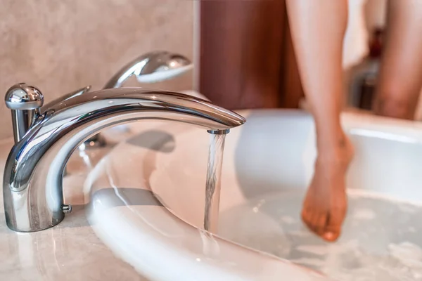 Mujer tomando un baño que entra en agua tibia con las piernas tocando el agua corriendo sumergiendo los dedos de los pies en la bañera de hidromasaje tiempo de relajación en casa. Estilo de vida hotel de lujo — Foto de Stock