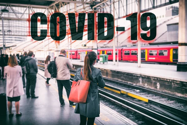 COVID-19 text sign travellers waiting at train station. Travel ban quarantine for public transport over Corona virus Coronavirus panic social distancing. Commuters crowd going to work commuting — Stock Photo, Image