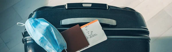 COVID-19 ταξιδιωτικός περιορισμός λόγω της μάσκας του ιού της κορώνας φορώντας υποχρεωτική μάσκα σε πτήσεις αεροδρομίου και αεροπλάνων προς Ευρώπη, Ασία. Διαβατήριο, εισιτήριο και βαλίτσα έτοιμα για διακοπές. Πανοραμική σημαία — Φωτογραφία Αρχείου