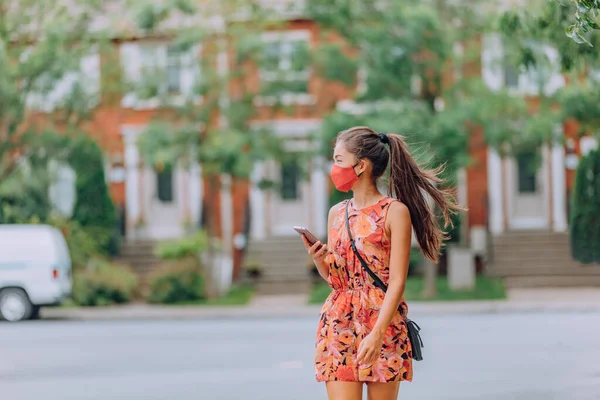 COVID-19女孩戴着面具走在城市街道上。强制穿着亚洲妇女使用手机通勤。城市公园室外夏季生活方式中的保护作用 — 图库照片