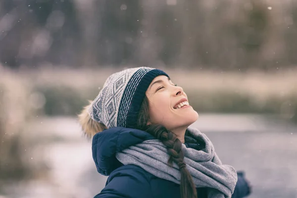 Inverno donna felice godendo la neve che cade sul viso esterno foresta natura asiatico ragazza guardando su indossare cappello e sciarpa freddo tempo vestiti — Foto Stock