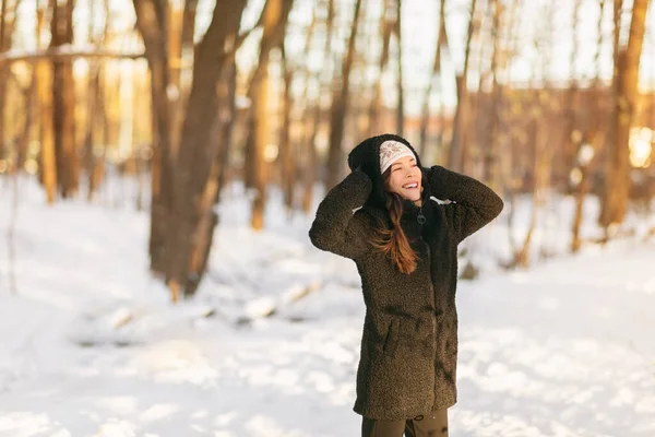 Зимний снег весело счастливая девушка ходить на улице в холодную погоду, защищая уши держа шерстяную шляпу над ушами активный образ жизни на открытом воздухе. Азиатка в пальто из шерпы Тедди, перчатки на свежем воздухе — стоковое фото