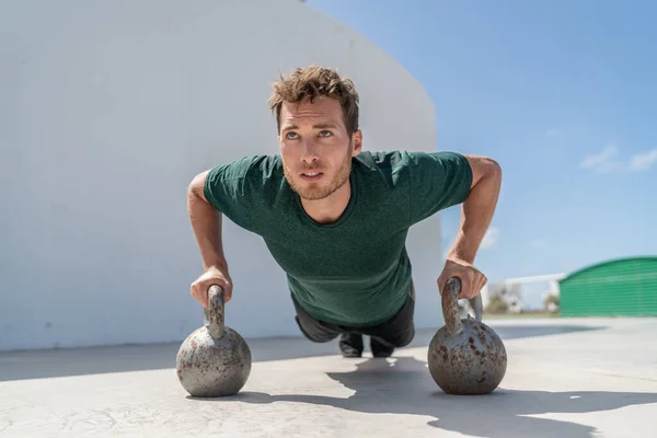Training fit man exercising pushup exercises on kettlebell weights in gym. Fitness athlete strength training body core doing push-ups holding on kettlebells bodyweight floor exercises at outdoor gym — Stock Photo, Image