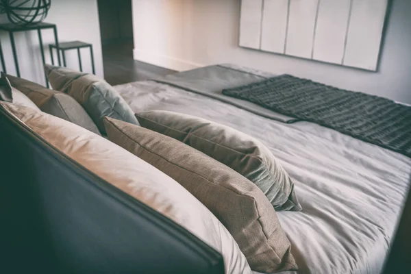 Κρεβάτι σε πολυτελές υπνοδωμάτιο στο δωμάτιο του ξενοδοχείου με μαύρο δερμάτινο κεφαλάρι και μαξιλάρια διακόσμησης, μοντέρνα εσωτερική διακόσμηση σουίτας — Φωτογραφία Αρχείου