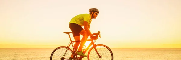 Atleta triahtlon uomo in bicicletta su strada corsa giro in bicicletta all'aperto al tramonto banner panorama paesaggio. Ciclista che si allena all'esterno con occhiali da sole e casco — Foto Stock