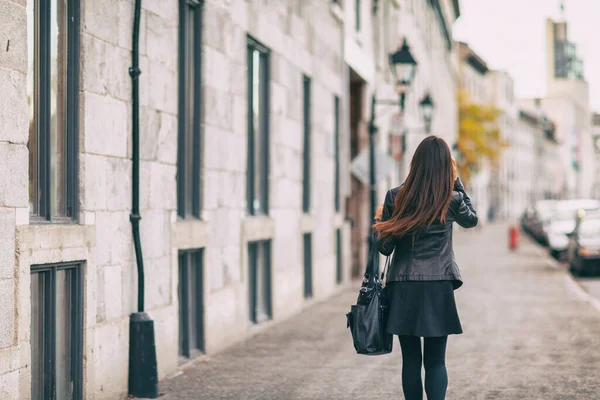 City street lifestyle persone pendolari giovane donna da dietro camminando fuori in autunno colori indossando giacca di pelle e gonna nera, lunghi capelli castani — Foto Stock