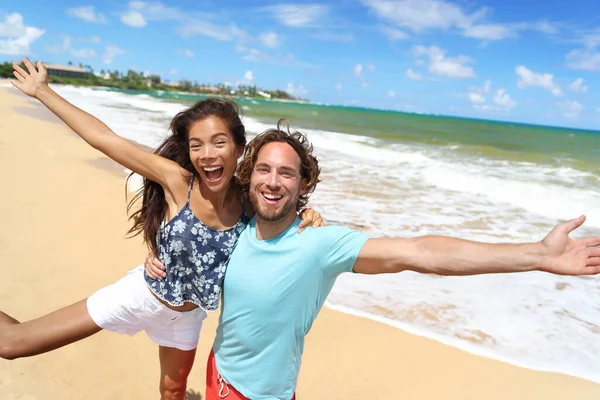 Pessoas felizes pulando gritando de diversão na praia férias de verão viajar no Havaí. Rindo jovem mulher asiática com homem caucasiano, turistas casal amigos de férias — Fotografia de Stock