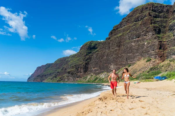 Hawaje lato zabawy młodych szczęśliwych ludzi działa na odludziu Kauai plaży, Polihale State Park. Hawajskie wakacje para turystów — Zdjęcie stockowe