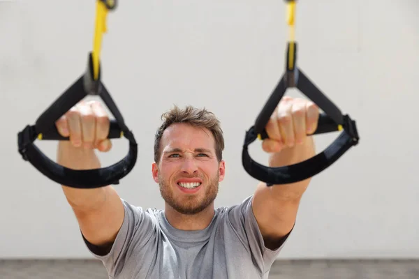 Bretelles de suspension exercices entraînement homme bras entraînement à la salle de gym extérieure. Athlète tenant des poignées trx suspendues faisant des pull-ups inclinés pour les muscles du dos — Photo