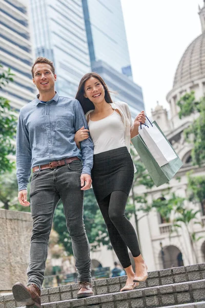 Frau und Mann beim Einkaufen in Hongkong Central. Ein gemischtes Paar geht mit Einkaufstüten nach draußen. Städtische gemischte Rasse asiatische chinesische Shopperin und kaukasischer Mann lächeln glücklich in der Stadt leben — Stockfoto