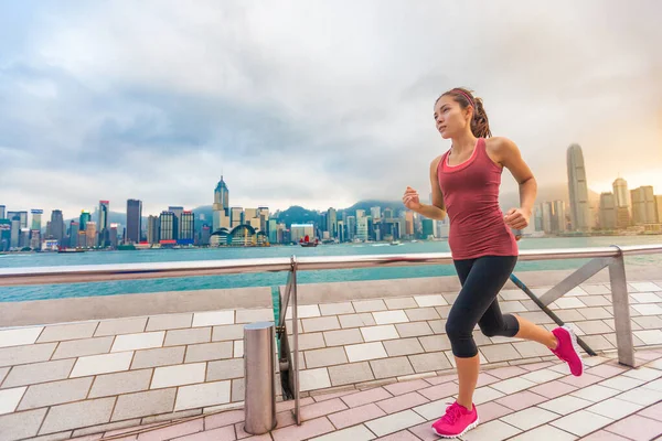 City Running - бегунья и гонконгский горизонт. Спортивная гимнастка, занимающаяся бегом трусцой на набережной Цим Ша Цуй и проспекте Звезд в гавани Виктория, Коулун — стоковое фото