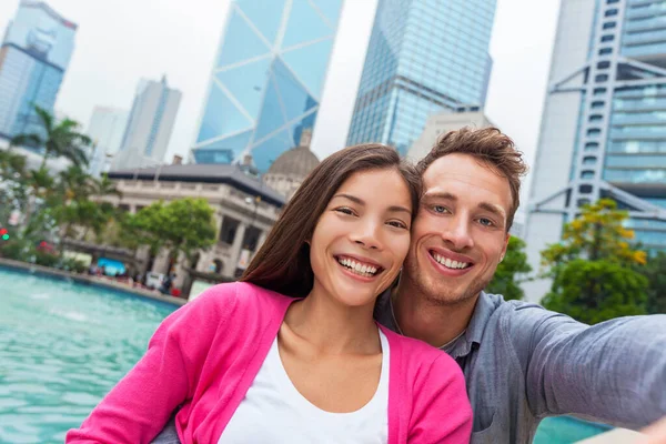 自私自利的游客将亚洲女人和白种人结合在一起，用手机拍照在香港、亚洲旅行的生活方式。两个人拍了一张自画像 — 图库照片