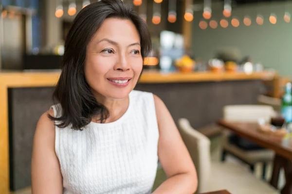 Happy healthy Asian middle-aged business woman relaxing inside restaurant. Beautiful mature Chinese business woman portrait in fancy restaurant in Shanghai, China. Beauty aging skin care — Stock Photo, Image