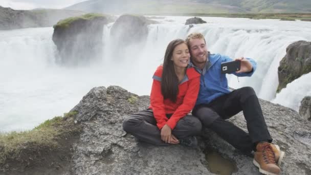 Casal tirando selfie contra a cachoeira Godafoss - Destino Turístico Islândia — Vídeo de Stock