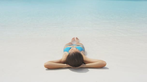 Расслабленная женщина загорает на пляже во время отпуска — стоковое видео