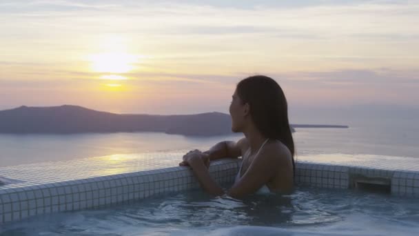 Mujer de vacaciones disfrutando de la puesta del sol en el spa en vacaciones de viaje en Santorini — Vídeo de stock