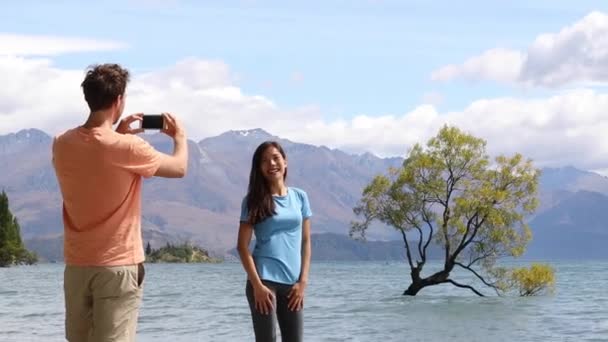Nowozelandzcy turyści robiący zdjęcia telefoniczne Wanaka Lone Tree nad jeziorem — Wideo stockowe
