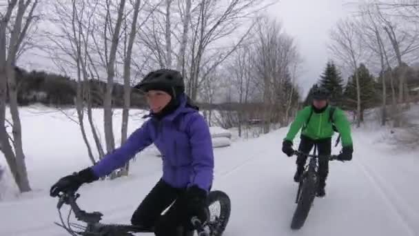 Fat bike in winter. Fat biker riding bicycle in the snow in winter. Selfie video by woman and couple living healthy outdoor active winter sports lifestyle — Stock Video