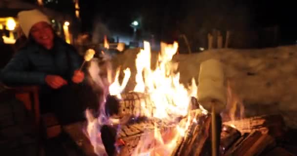 Зимний отдых женщина горнолыжного курорта жарят зефир в барбекю Firepit после лыжного развлечения развлечения с друзьями. Пара палочек зефира в огне — стоковое видео