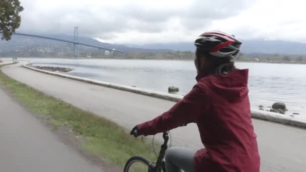 Radfahrerin radelt im Stanley Park an der Lions Gate Bridge am Vancouver Seawall — Stockvideo