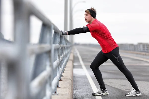 Homem atleta alongamento pernas no inverno ao ar livre correr — Fotografia de Stock