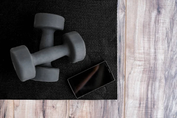 Gym fitness mat with free weights mobile phone app — Stock Photo, Image