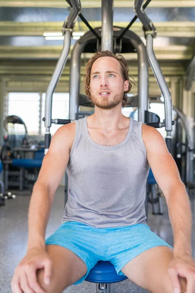 Hombre haciendo ejercicio tomando un descanso en el equipo de fitness —  Fotos de Stock