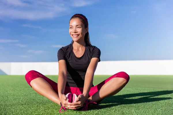 Feliz fitness asiática mujer estirando piernas en parque — Foto de Stock